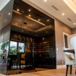Glass walls and LED lighting are beautiful components of this transitional home wine cellar.